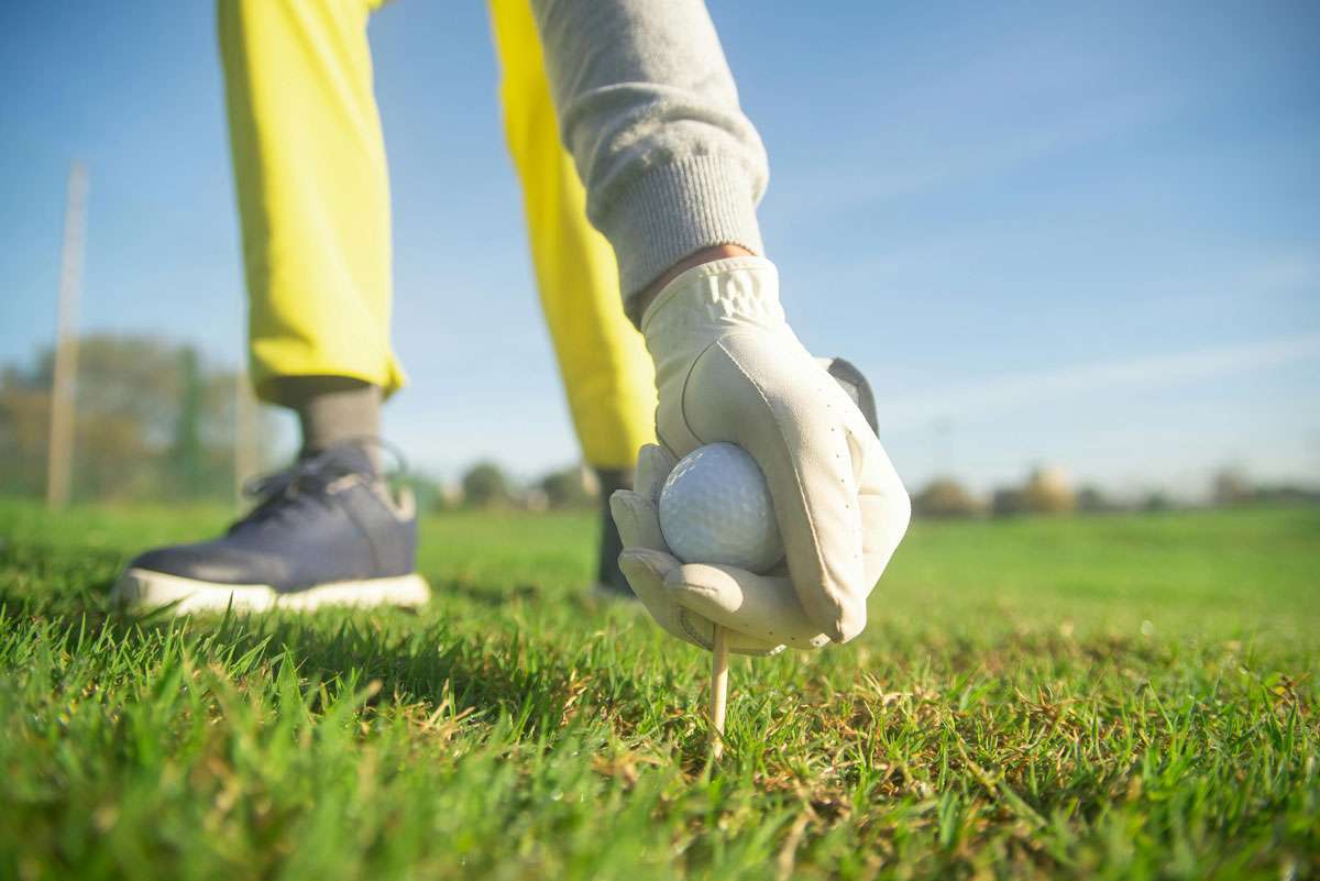 stock photo of person placing golf ball on golf tee