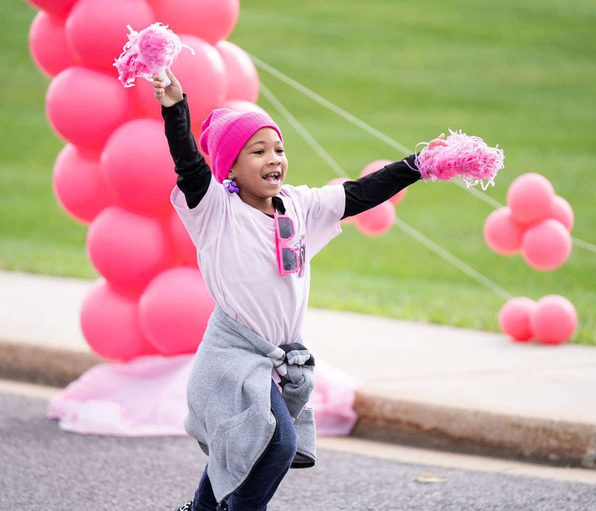 young girl with pink balloons at cancer benefit event