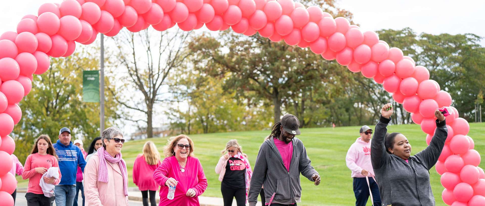 group of people walking under pink ballons at a breast cancer fundraising event